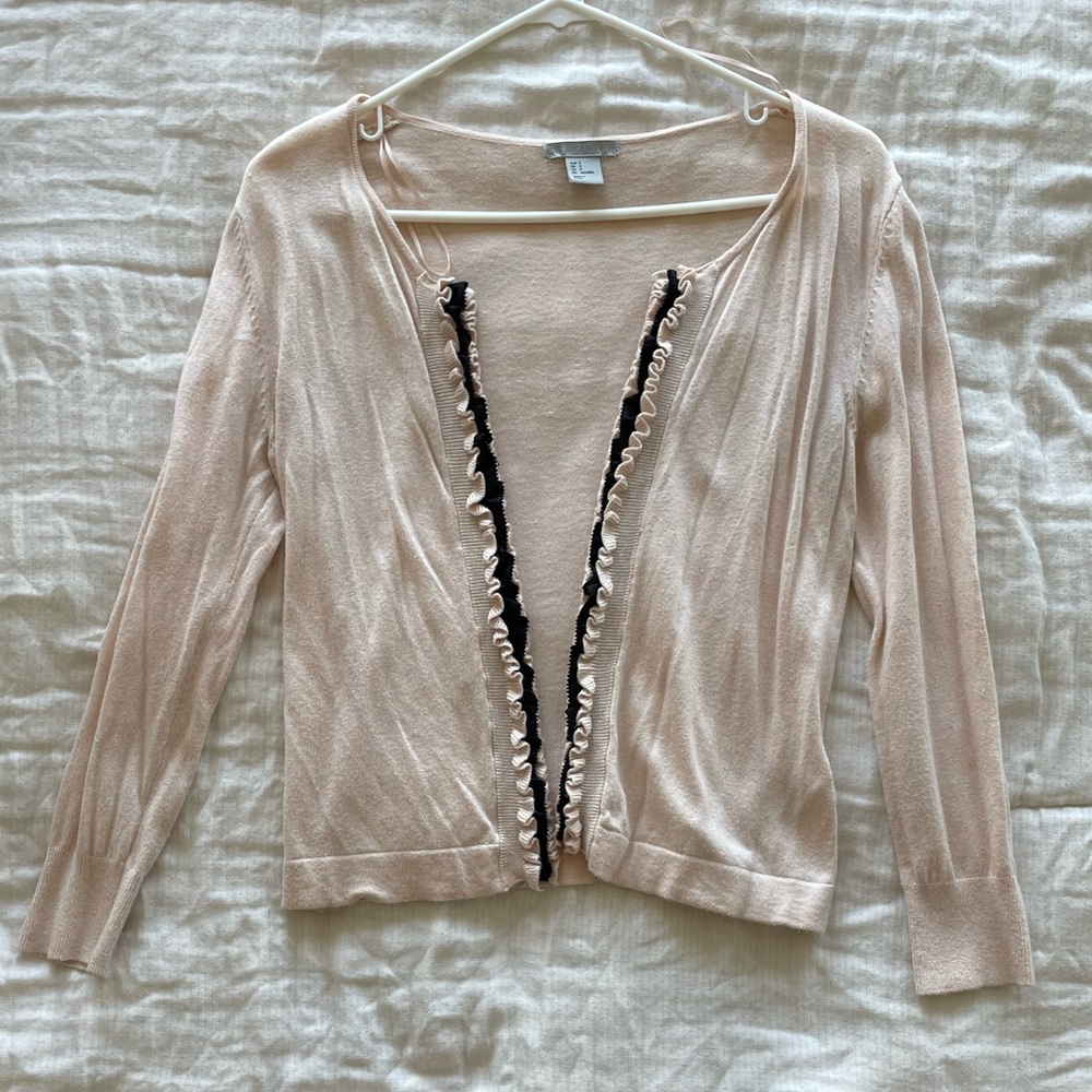 Pink cardigan with black ruffles.